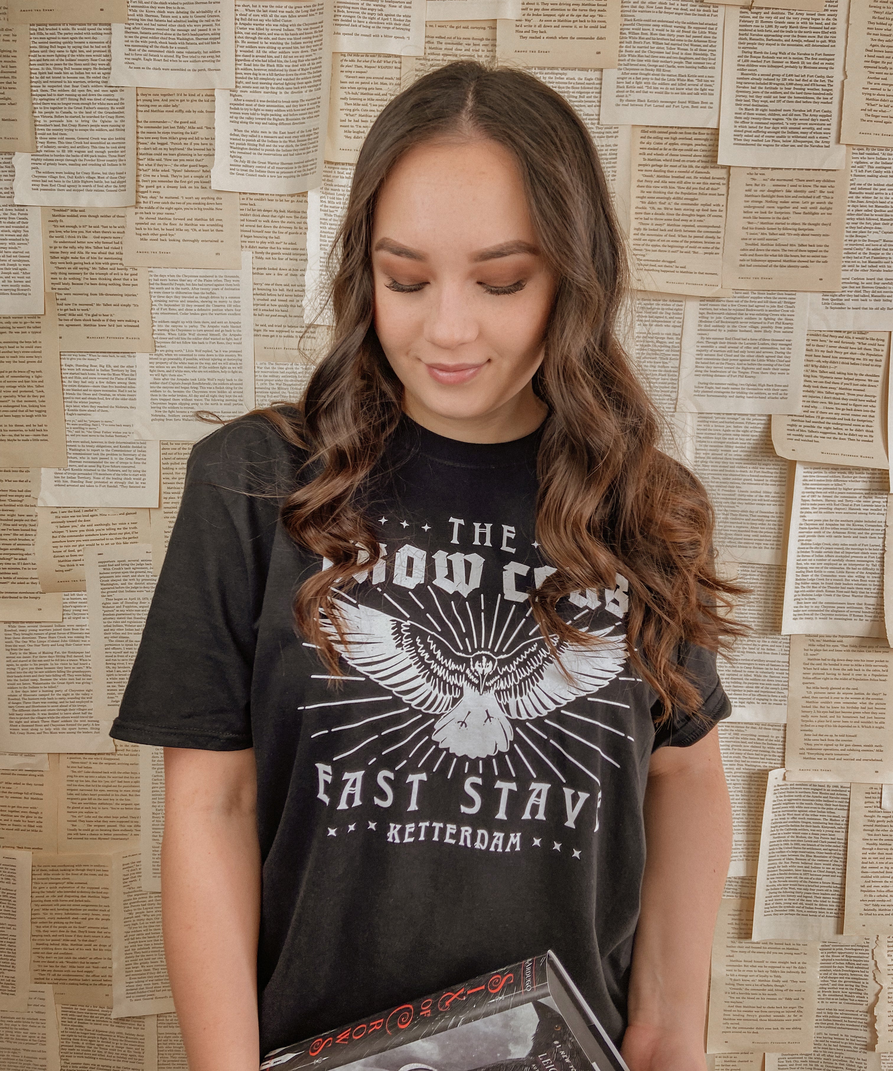 model wearing crow club t-shirt while holding a book