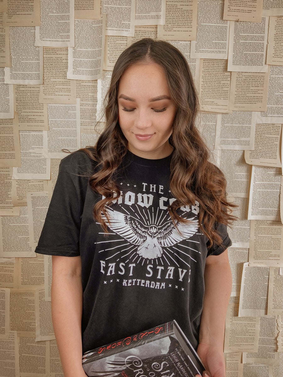 model wearing crow club t-shirt while holding a book