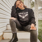 model woman sitting on stairs with crow club sweatshirt on